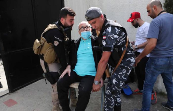 عنصران من الأمن يحملان مسناً إلى مركز الاقتراع